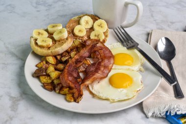 Patates kızartmalı sahanda yumurta ve domuz pastırması yanında da fıstık ezmeli ve muzlu kek.