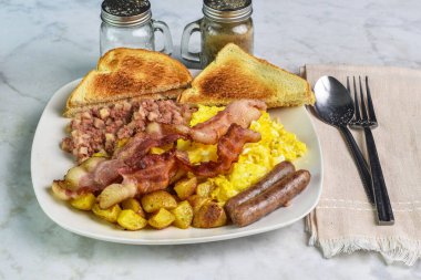 Çırpılmış yumurta, domuz pastırması, sosis, yanında mısır gevreği ve patates kızartması.,