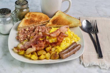 Çırpılmış yumurta, domuz pastırması, sosis, yanında mısır gevreği ve patates kızartması.,