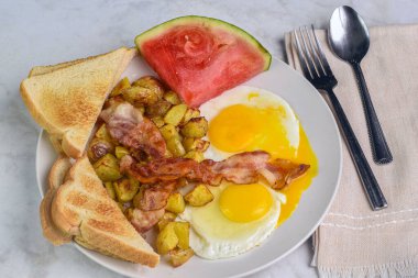  Jambonlu sahanda yumurta, patates kızartması ve bir dilim karpuz.