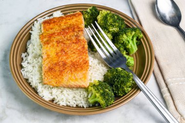 Izgara somon, pilav ve brokoli ile servis edilir.