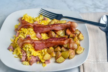 Domuz pastırması ve patates kızartması ile servis edilmiş jambonlu omlet.