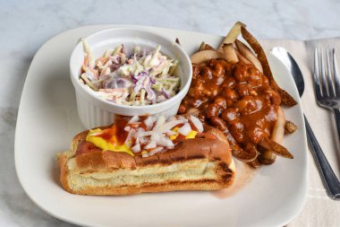 Hardallı sosisli, ketçaplı ve soğanlı lahana salatası ve acılı patates kızartması.