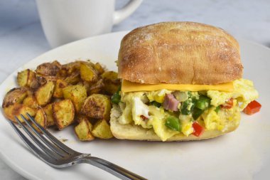 Biber dilimlenmiş yumurta, soğan ve ciabatta ekmeğinde servis edilen peynirli jambon.