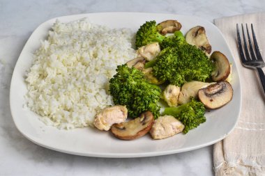 Buğulanmış brokoli ve sotelenmiş mantarla servis edilen beyaz pirinç.