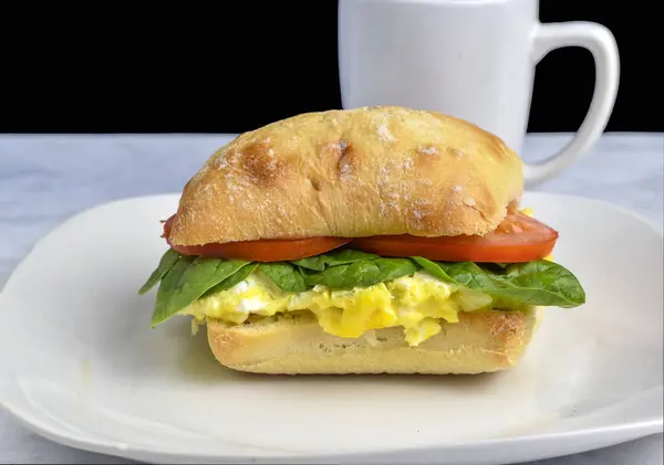 Çeşnili yumurta üstü, ciabatta rulosunda servis edilen domatesli.