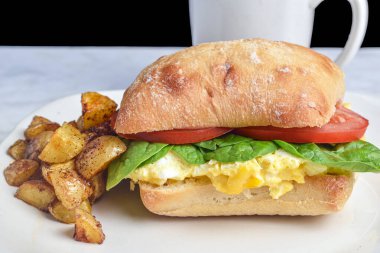 Çeşnili yumurta üstü, ciabatta rulosunda servis edilen domatesli.