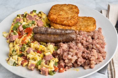 Konserve jambonlu omlet, soğan ve haşlanmış mısır, patates ve sosis ile servis edilir., 