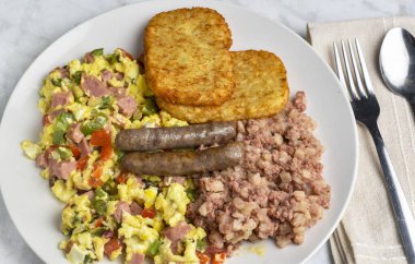 Konserve jambonlu omlet, soğan ve haşlanmış mısır, patates ve sosis ile servis edilir.,