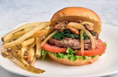 Hamburger, domates, marul üstü, sotelenmiş ıspanak, soğan ve mantarlı çörek..