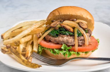 Hamburger, domates, marul üstü, sotelenmiş ıspanak, soğan ve mantarlı çörek..