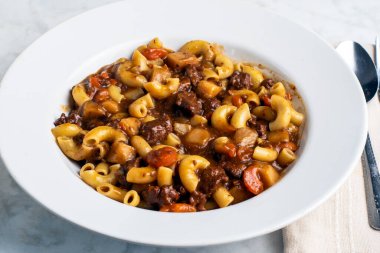 Makarna, bol etli güveç ile servis edilir.