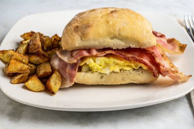 Çırpılmış yumurta ve pastırmalı sandviç, yanında patates kızartması.,