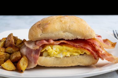 Çırpılmış yumurta ve pastırmalı sandviç, yanında patates kızartması.,