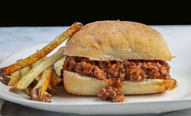  Ciabatta rulosunda yanında patates kızartmasıyla servis edilen kıymalı sandviç.,