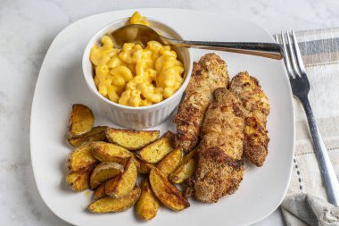 Patates, makarna ve peynirle servis edilen tavuklar.