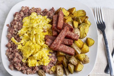 Yağda yumurta ve mısır ezmesi yanında patates kızartması ve patates kızartması.