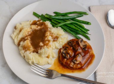 Soğan soslu salisbury bifteği ve patates püresiyle servis edilen mantarlar.