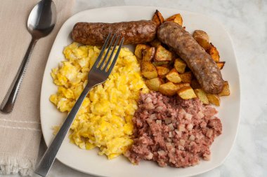 Çırpılmış yumurta, tatlı İtalyan sosisi, patates kızartması ve mısır gevreği.,