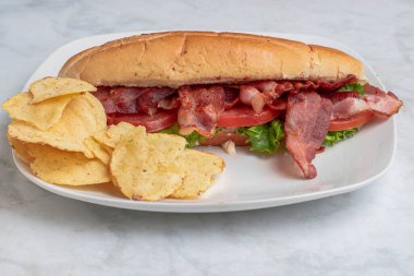 Domuz pastırması, marul ve patates cipsiyle servis edilen domates.,