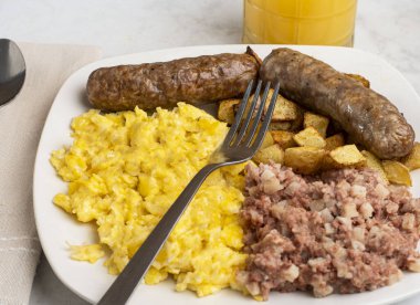 Çırpılmış yumurta, tatlı İtalyan sosisi, yanında mısır gevreği ve orangutan suyu.