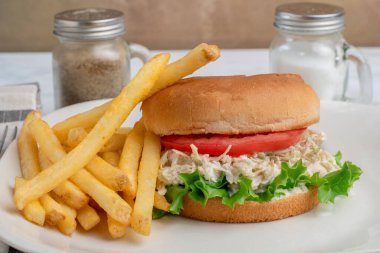 Marullu tavuk salatası ve patates kızartması ile servis edilen bir çörek.