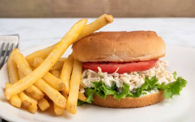 Marullu tavuk salatası ve patates kızartması ile servis edilen bir çörek.