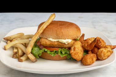 Marul, domates ve tart soslu mezgit filetosu patates kızartması ve karides ile servis ediliyor.