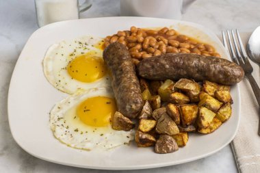 Maydanozlu sahanda yumurta, fırında fasulye, patates kızartması ve tatlı İtalyan sosisi.,