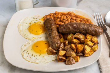 Maydanozlu sahanda yumurta, fırında fasulye, patates kızartması ve tatlı İtalyan sosisi.,