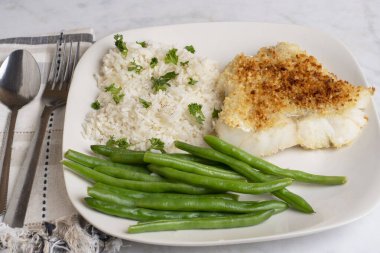 Fırında mezgit, pirinç, maydanoz ve yeşil fasulye ile servis edilir.