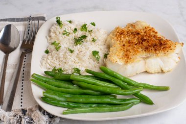 Fırında mezgit, pirinç, maydanoz ve yeşil fasulye ile servis edilir.