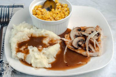 Domuz pirzolasında soğan ve mantar patates püresi ve mısır sosuyla servis edilir.,