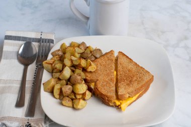 Kızarmış yumurta eritilmiş kahvaltı sandviçi ve patates kızartması.