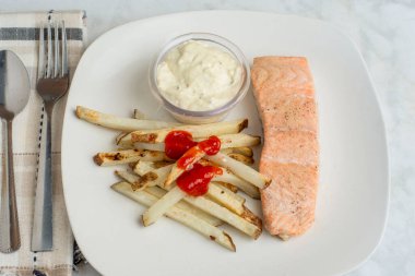 Biber sarımsaklı fırında somon balığı ve patates kızartmasıyla servis edilen soğan tuzu.,,