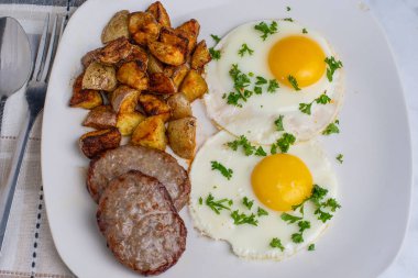 İki sahanda yumurta ve maydanozlu sosisli börek ve patates kızartması.