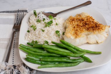 Fırında mezgit, pirinç, maydanoz ve yeşil fasulye ile servis edilir.