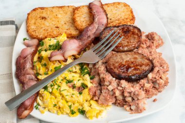 Çırpılmış yumurta, maydanozla servis edilmiş mısır, domuz pastırması ve sosisli börek.,