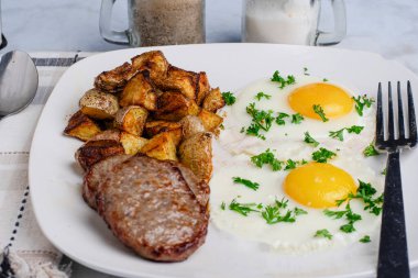 İki sosisli börek ve patates kızartmasıyla birlikte maydanozlu sahanda yumurta.
