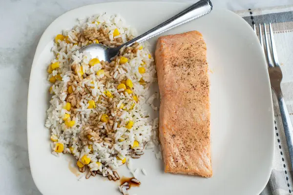 biber, sarımsak ve soğan tuzu ve mısır ve soya soslu pirinç ile servis edilmiş somon balığı üstü.