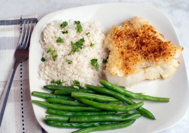 fırında mezgit filetosu, pirinç üstü maydanoz ve yeşil fasulye ile servis edilir.