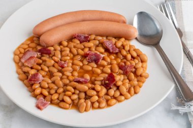 two natrual casing hot dogs served with baked beans top with bacon bits,  clipart