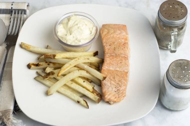 Biber sarımsaklı fırında somon balığı ve patates kızartmasıyla servis edilen soğan tuzu.,,