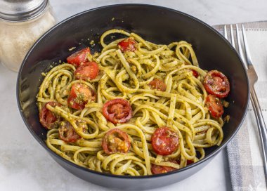 Pesto ve domatesle servis edilen spagetti.