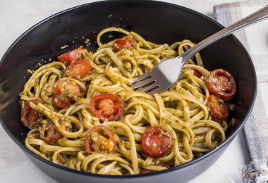Pesto ve domatesle servis edilen spagetti.
