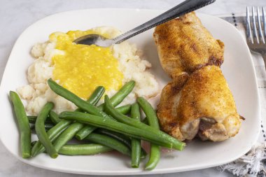  Baharatlı tavuk budu. Patates püresi ve kremalı mısır ile servis ediliyor.,