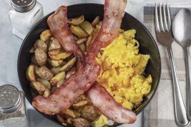 Çırpılmış yumurta ve patates kızartması. Üstü bocon ile servis edilmiş.