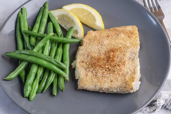 Haşlanmış taze fasulyeyle servis edilen kızarmış morina balığı. 