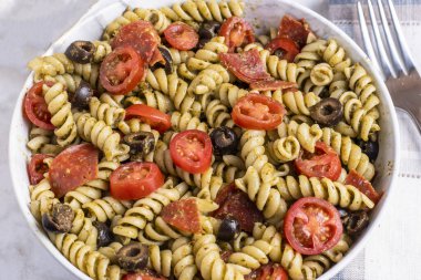 Domates, zeytin ve pepperoniyle servis edilen soslu rotini..