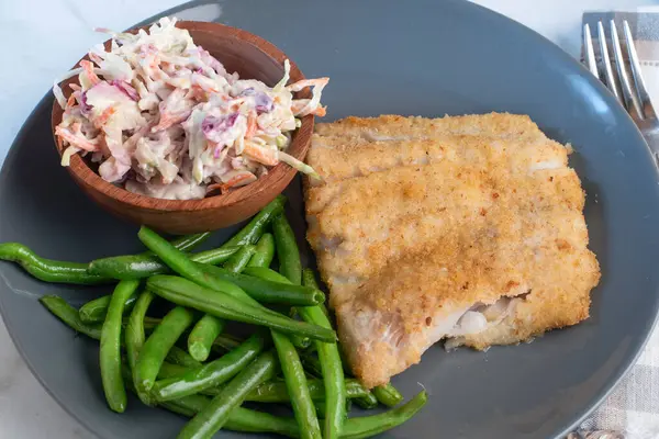 Fırında mezgit yanında sotelenmiş yeşil fasulye ve lahana salatası.